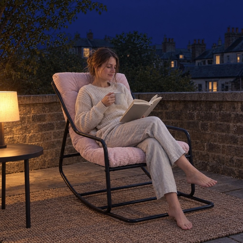 Femme qui lit avec une tisane dans le fauteuil à bascule BELLE ÉTOILE, sur la terrasse le soir